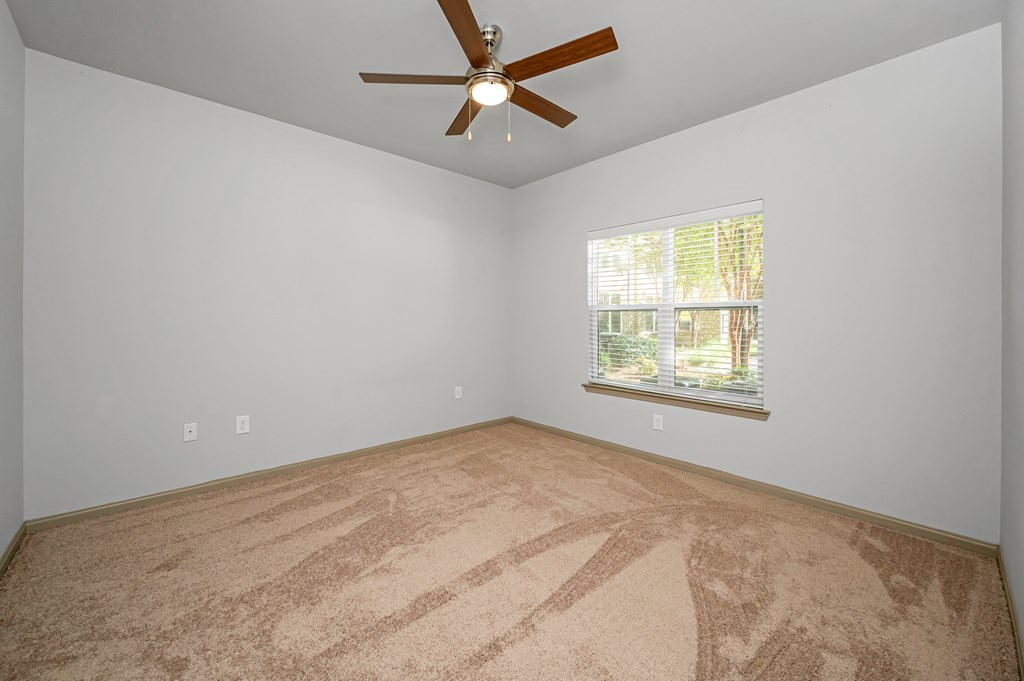 A room with a ceiling fan and a window with blinds.